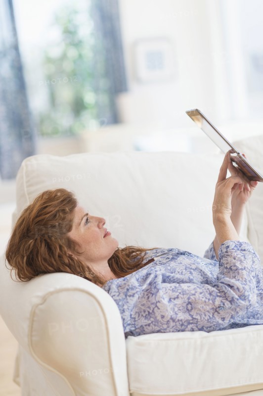 Woman lying on sofa and using laptop.