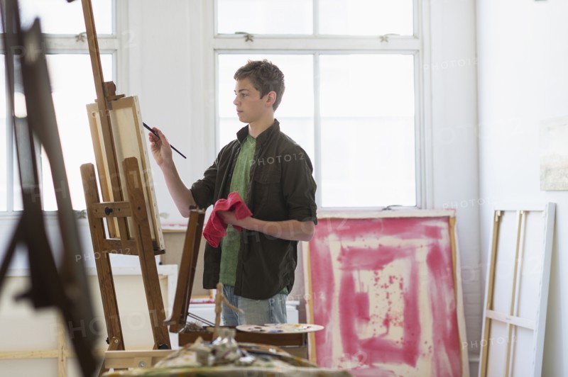 Teenage boy (16-17) painting picture.