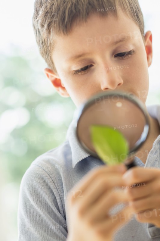 boy (8-9) looking through magnifying glass.