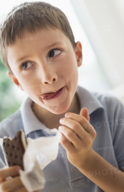 boy (8-9) eating ice cream sandwich.