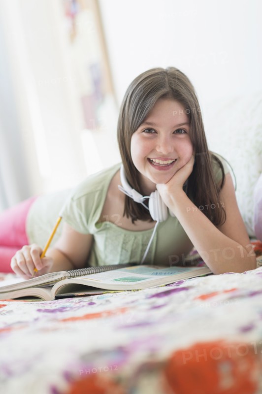 girl (10-11) lying in bed and learning.