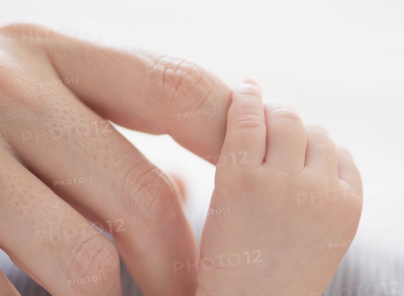 Close up of mother's hand touching baby boy's(2-5 months) foot.