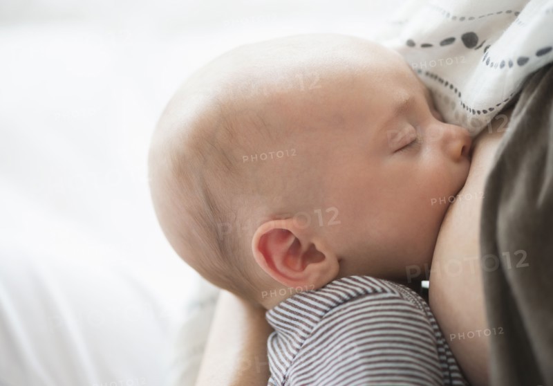 Close up of baby boy (2-5 months) suckling mother's breast.