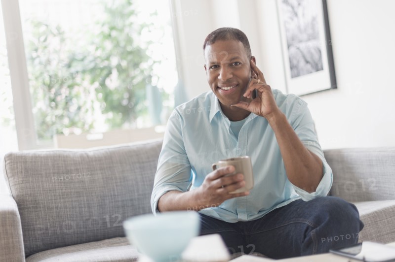 Portrait of man sitting on sofa at home.