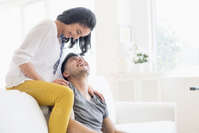 Happy young couple playing on sofa.