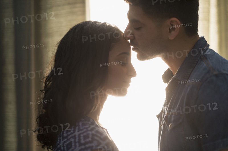 Young couple kissing in sunlight.