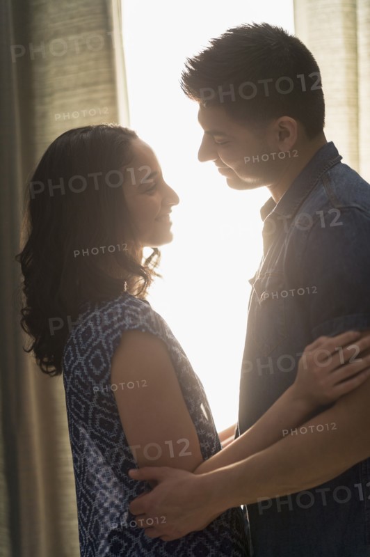 Young couple embracing in sunlight.