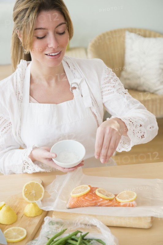 Young woman seasoning salmon.
Photo : Jamie Grill