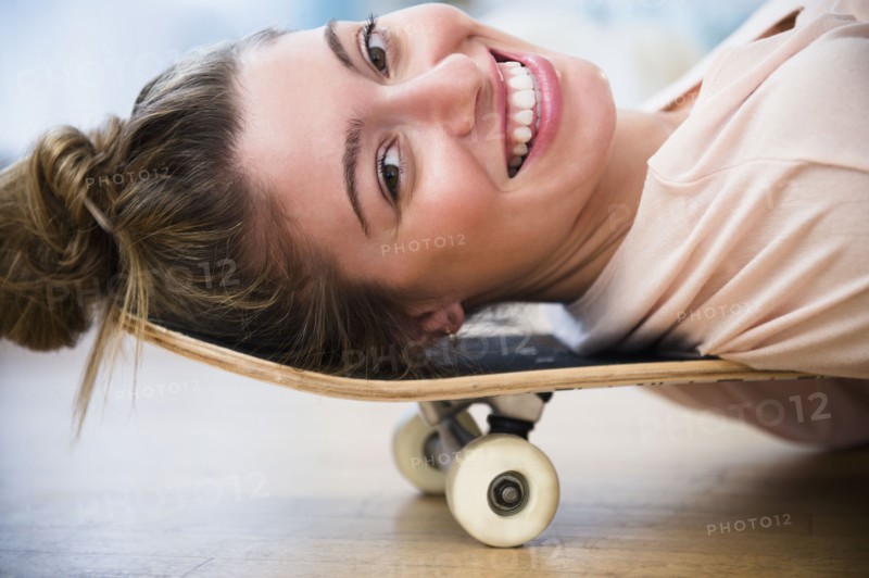 Portrait of young woman lying down on skateboard.
Photo : Jamie Grill