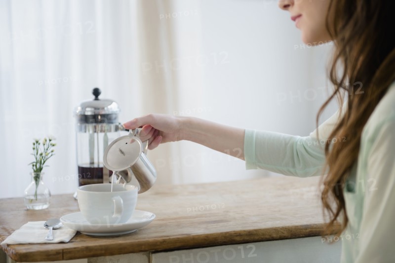 Young woman pouring milk into coffee cup.
Photo : Jamie Grill