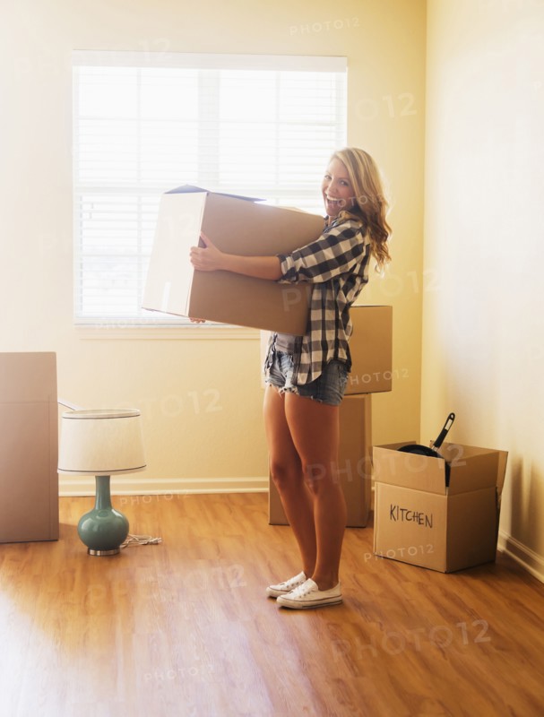Young woman carrying box in her new house.
Photo : Daniel Grill