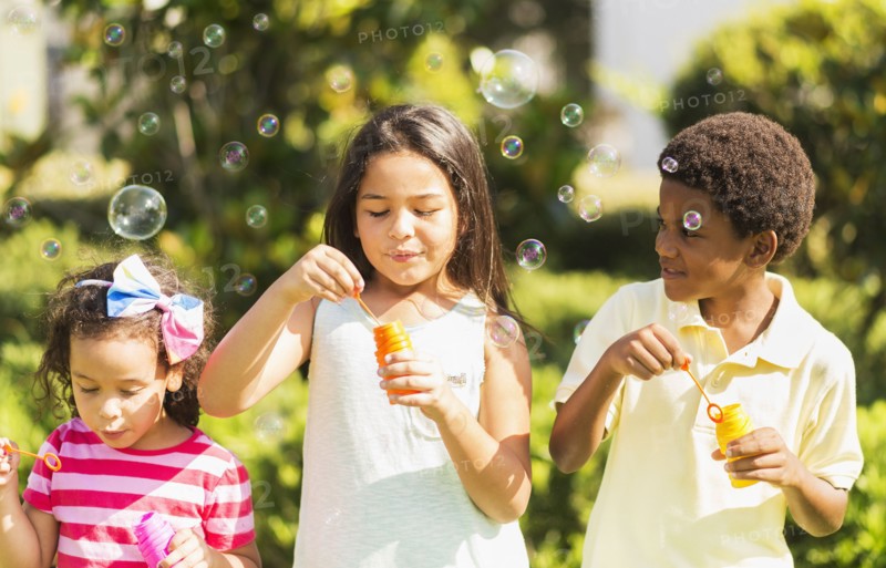 Girls( 4-5, 8-9) and boy (6-7) blowing soap bubble.
Photo : Daniel Grill