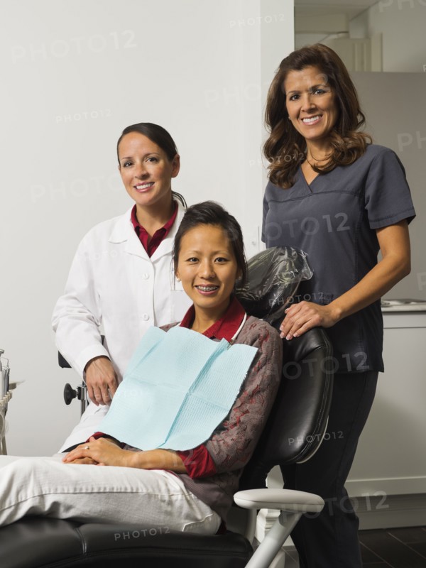 Portrait of dentist with patient and assistant.