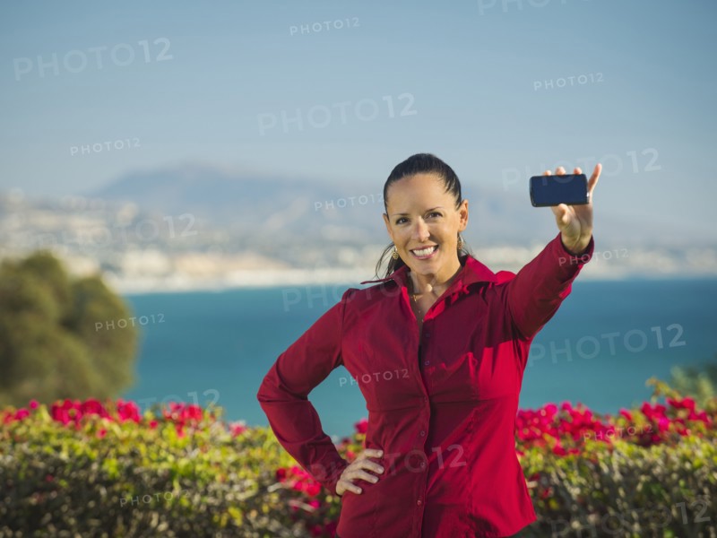 Portrait of smiling woman holding smartphone.