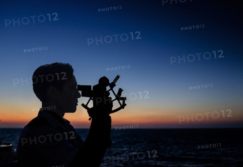 Man looking through sextant.