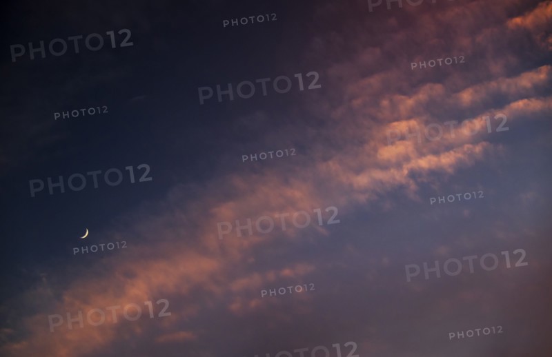 Moon against cloudy sky at sunset.