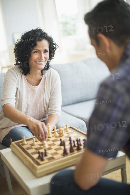 Couple playing chess in living room.