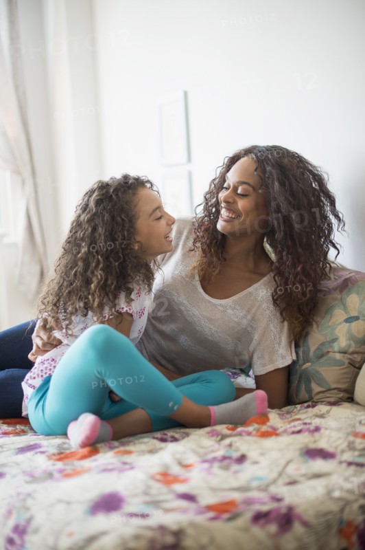 Mother and daughter (8-9) sitting on bed.