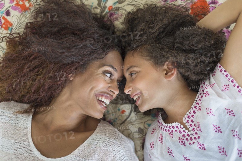 Mother and daughter (8-9) lying on bed.