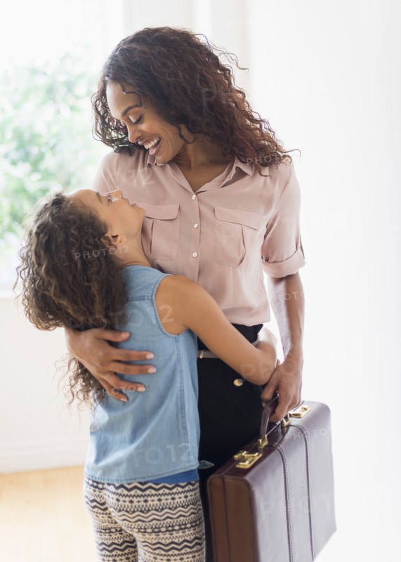 Mother walking in home, daughter (8-9) welcoming her.