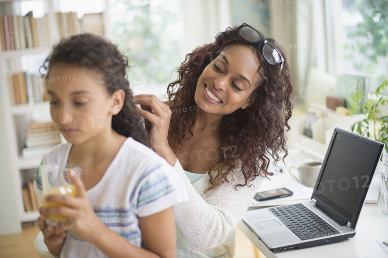 Woman braiding (8-9) daughter's hair.