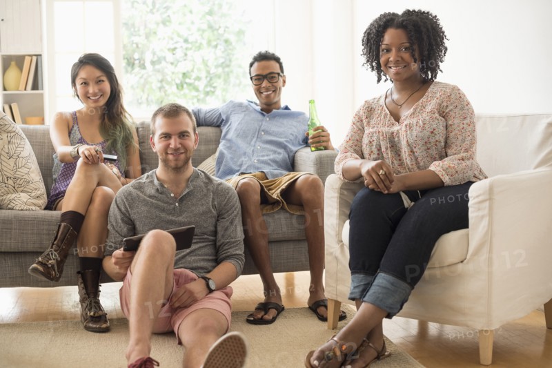 Portrait of group of friends sitting in living room.