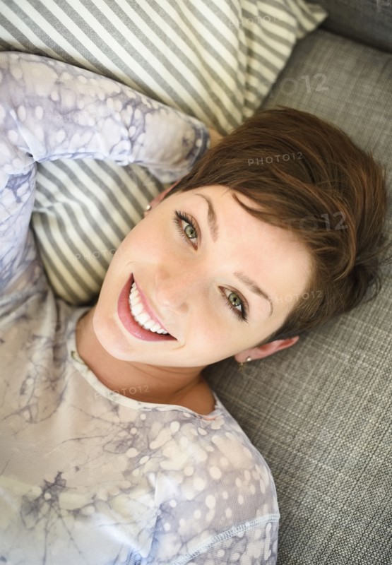 Portrait of smiling woman lying on sofa.
