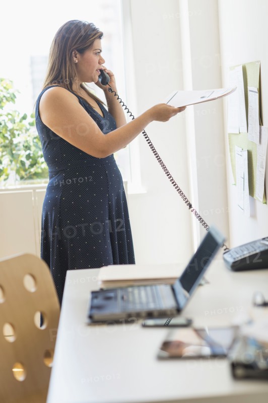 Woman using telephone in office.