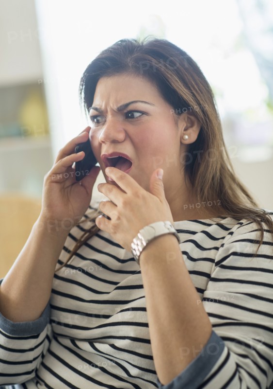 Surprised woman sitting on sofa with mobile phone.