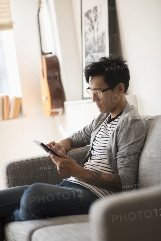 Man sitting on sofa and using tablet.