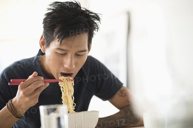 Man eating noodles with chopsticks.