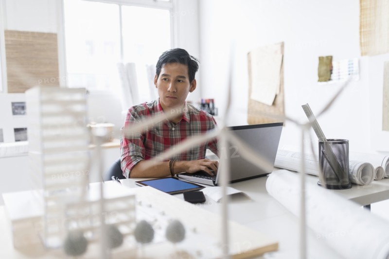 Wind turbine models on desk in front of architect.