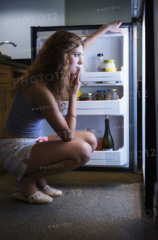 Young woman looking into refrigerator.