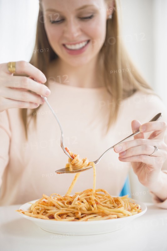 Young woman eating fettuccini