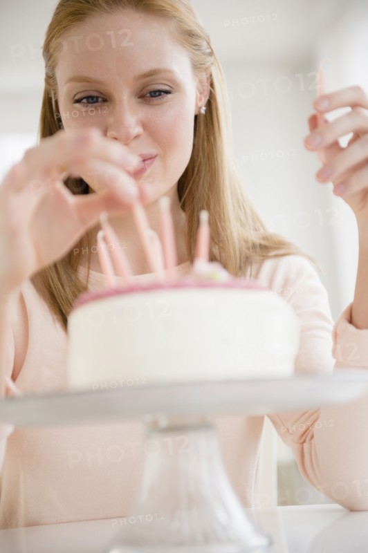 Woman putting candles on birthday cake