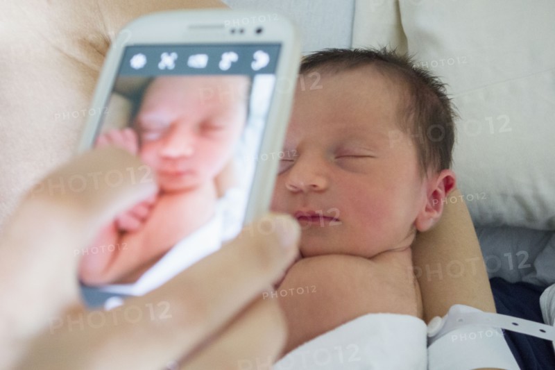 Mother photographing newborn daughter