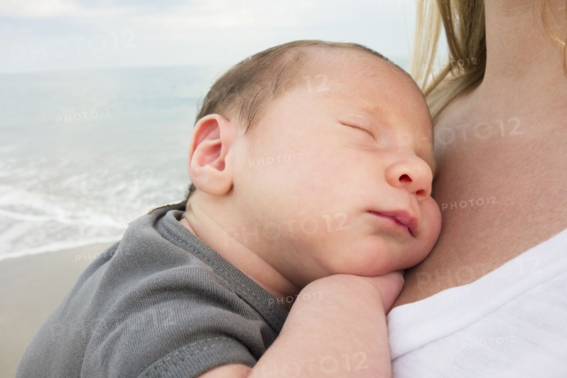 Mother holding newborn daughter on beach