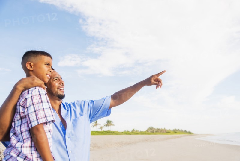 Father and son (10-11) embracing on beach