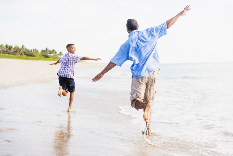 Father and son (10-11) running on beach