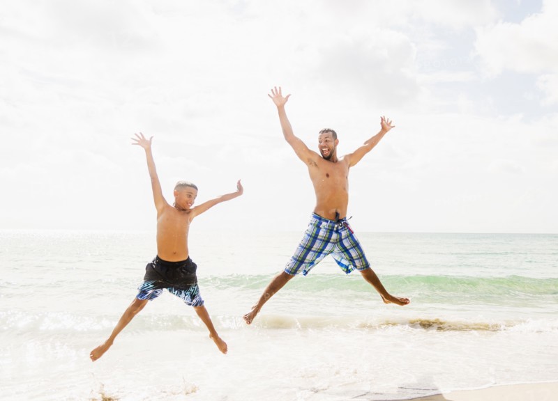 Father and son (10-11) having fun on beach