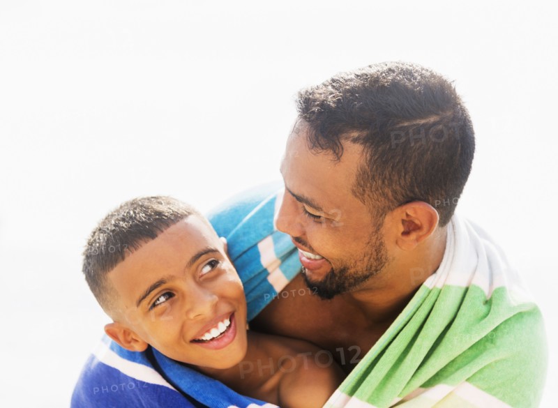 Father and son (10-11) embracing on beach