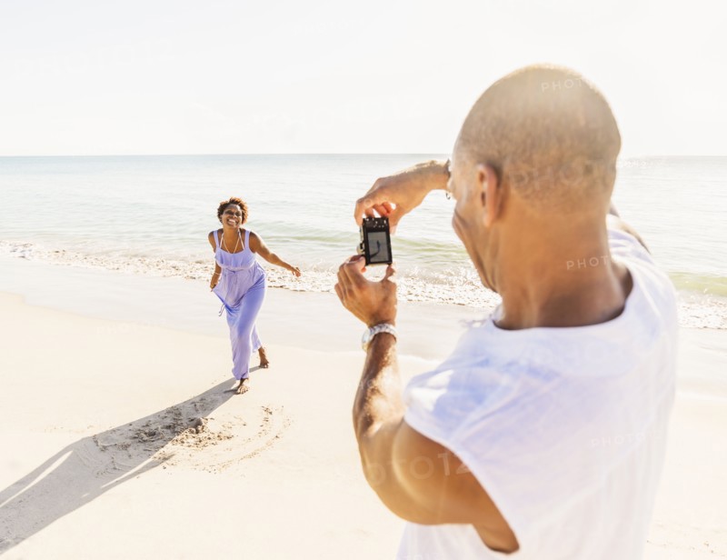 Man photographing woman on beach