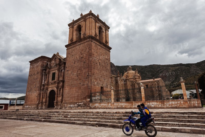 Two boys on motorcycle passing near old church