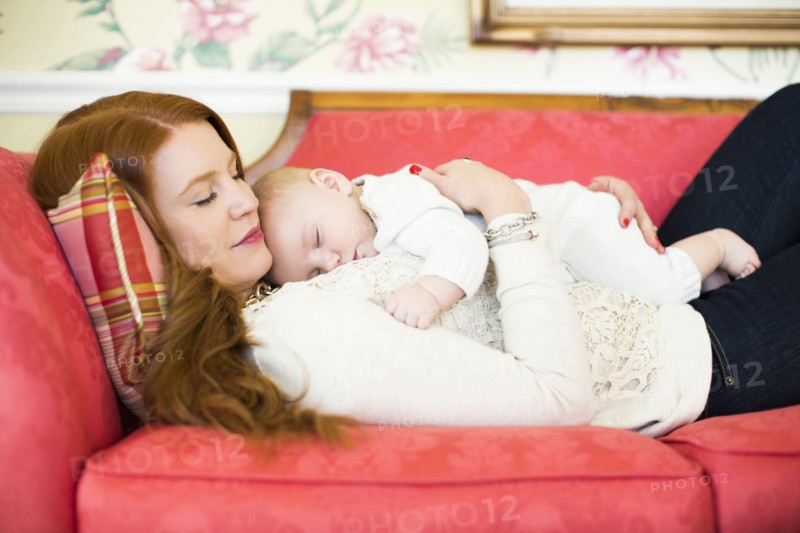 Mid adult woman napping with her baby boy (2-5 months)