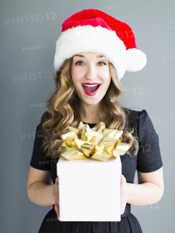 Studio portrait of woman wearing Santa hat holding gift