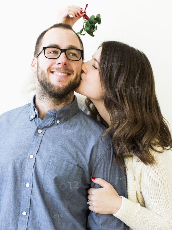 Woman kissing man under mistletoe
