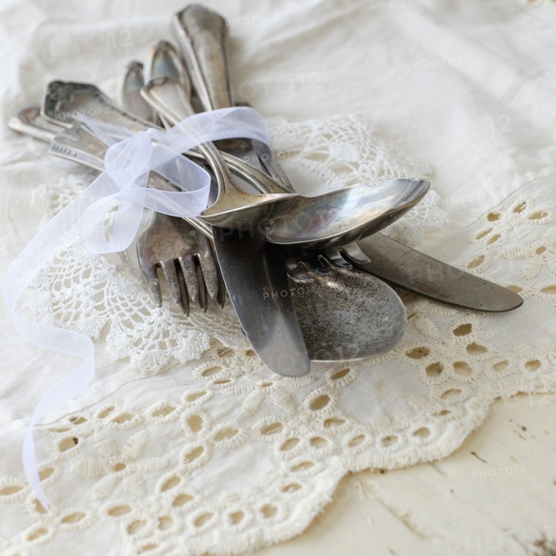 Studio shot of cutlery on lace cloth.