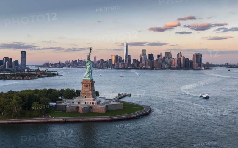 Aerial view of city with Statue of Liberty at sunset. New York City, New York.