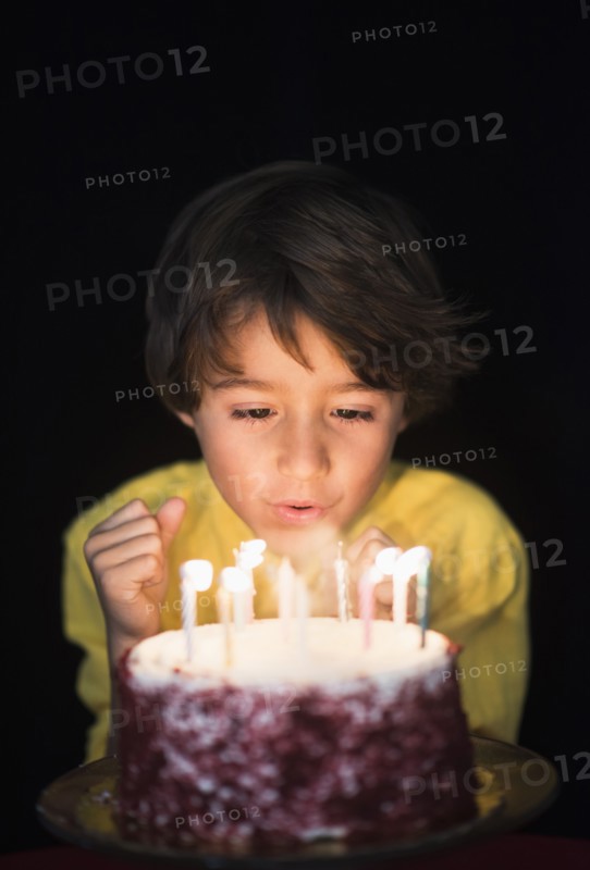 Portrait of boy (6-7) blowing out birthday candles.