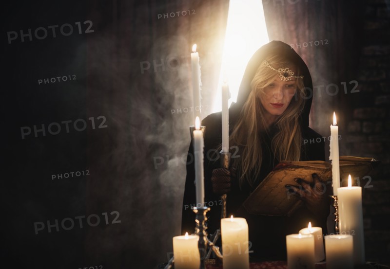 Sorceress reading book in dark room.